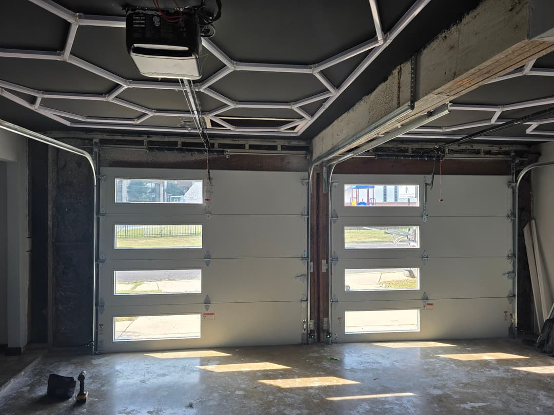 Two modern garage doors with windows, open in a newly renovated garage space.