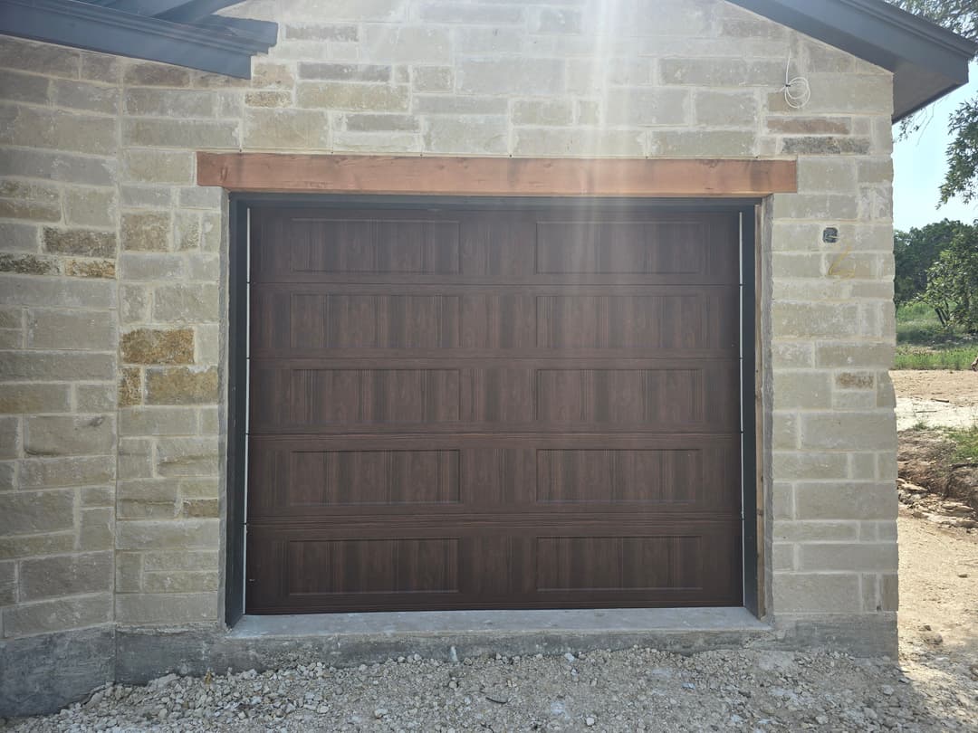 Wooden garage door on a stone house exterior with natural light shining.