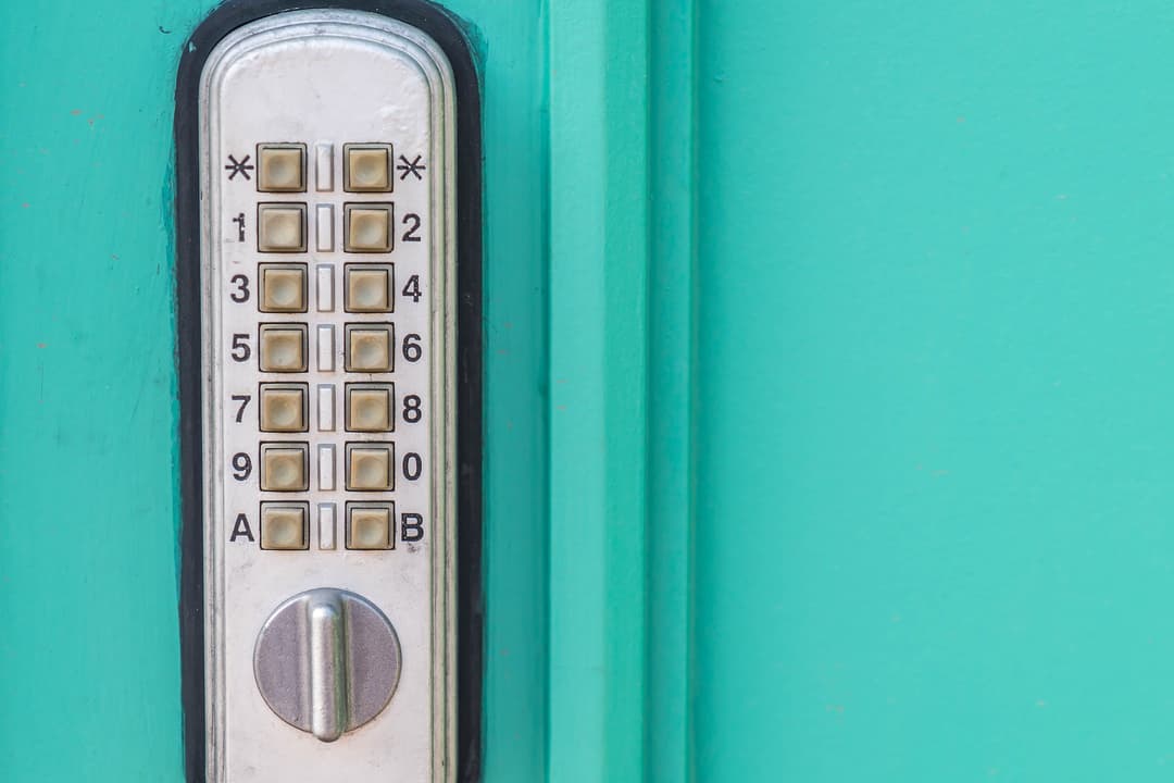 Digital keypad lock on a turquoise door for secure access.