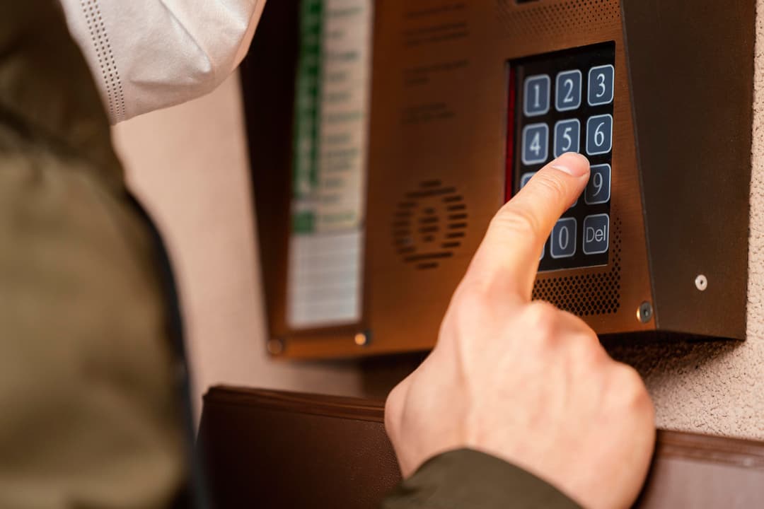 Person pressing a keypad to unlock a door in an apartment building.