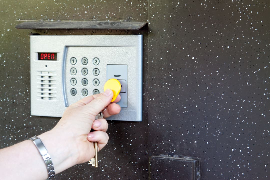 Hand using a keypad to unlock a door with a keycard at a modern entry system.