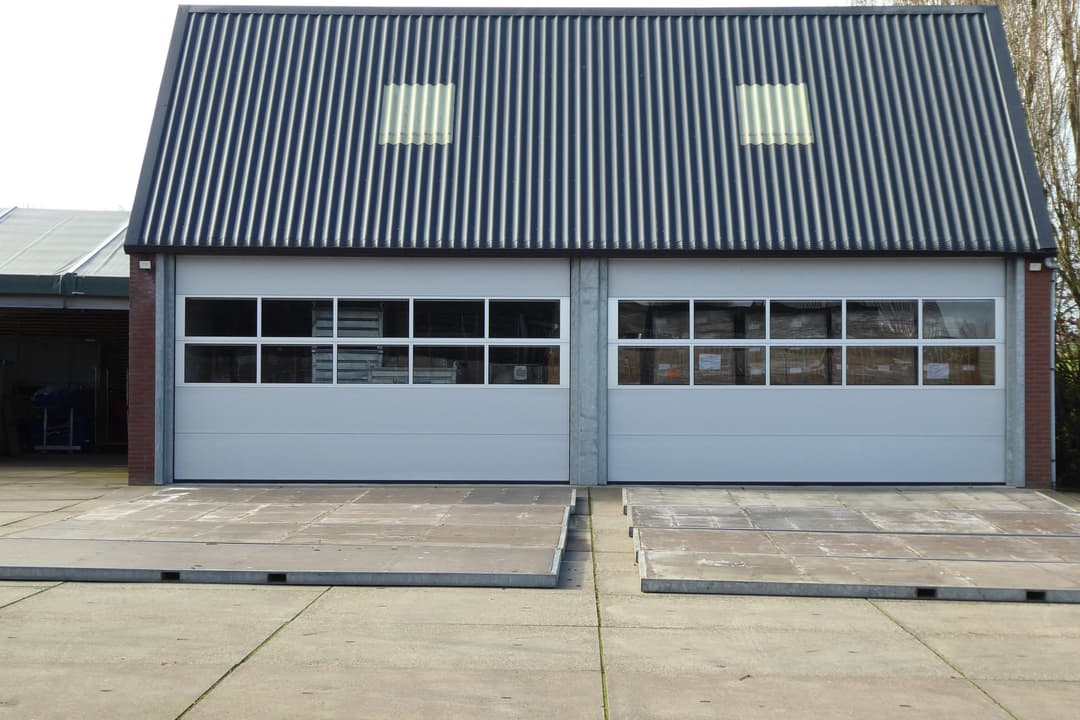 Modern industrial building with two large garage doors and a metal roof.