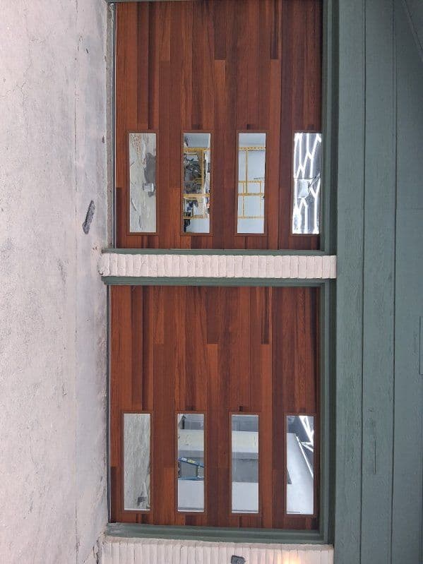 Modern wooden garage doors with glass panels, showcasing a stylish exterior design.