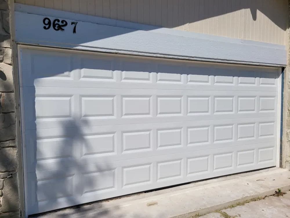 White garage door with raised panel design, featuring house number 9627 above it.