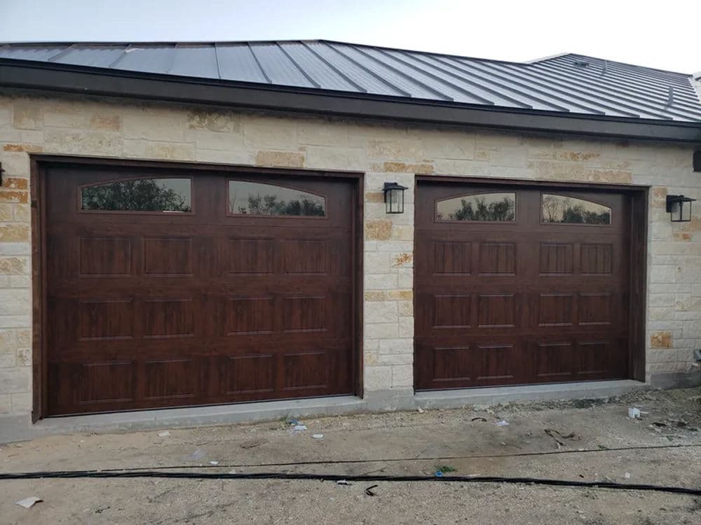 Wooden garage doors with windows on a stone house exterior. Modern and stylish design.